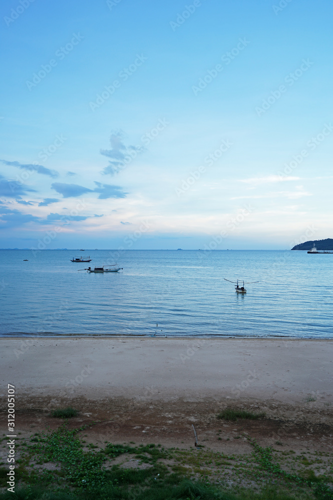 View of seascape with long tail boats, seashore sand and green island with cloudy blue sky- Chumphon,Thailand