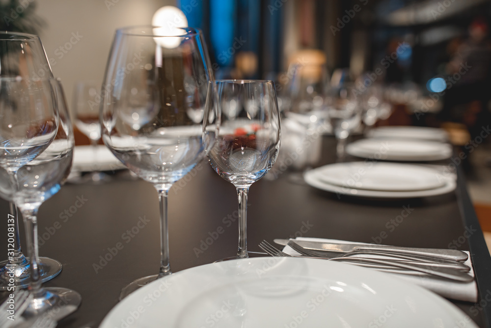 Empty Glasses, forks, knives, plates on a table in restaurant served for dinner