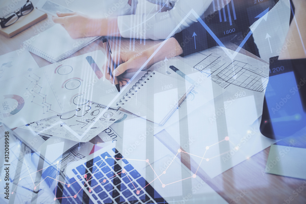 A woman hands writing information about stock market in notepad. Forex chart holograms in front. Concept of research. Double exposure
