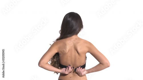 Close-up of woman with long wavy brunette hair taking off her black lingerie. Isolated, on white background photo