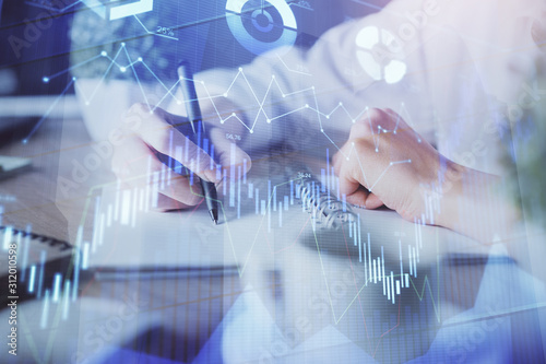 Financial forex graph displayed on hands taking notes background. Concept of research. Double exposure