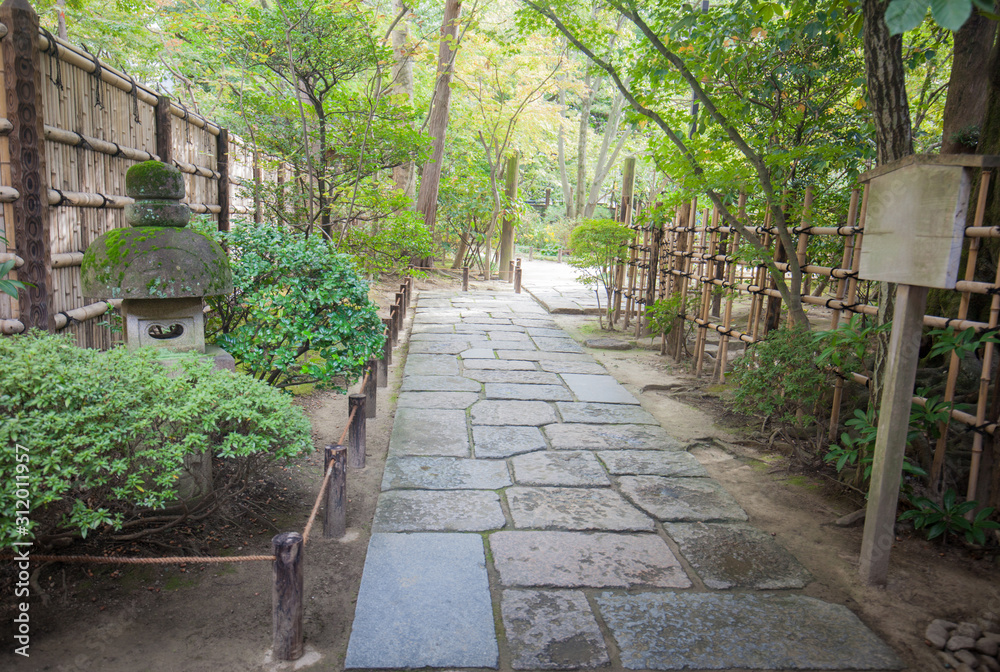 Path of plated stones among the Green trees in Japanese Garden. Meditative stone walkway. Garden architecture, pathway accessory to garden. the park at morning. Black rocks walking way in tropical.