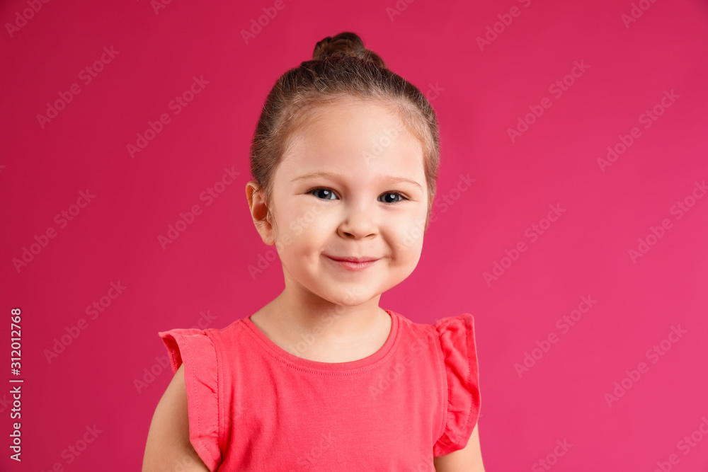Portrait of cute little girl on pink background