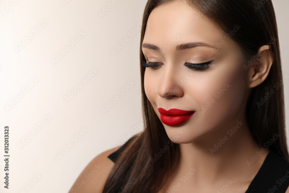 Fototapeta premium Beautiful woman with red lipstick on light background, space for text