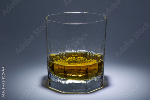 A glass of whiskey with ice. Art installation with lighting from above and close-up.