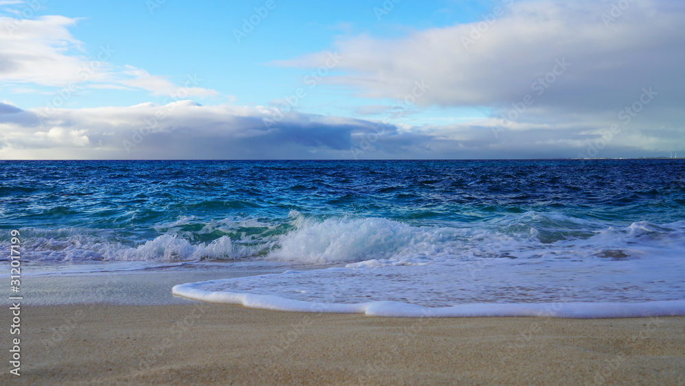 Tropical beach white sand, blue clear ocean water. sea ​​foam on the beach on a sunny day. sea waves on the shore. surf breaking on shore at sunset