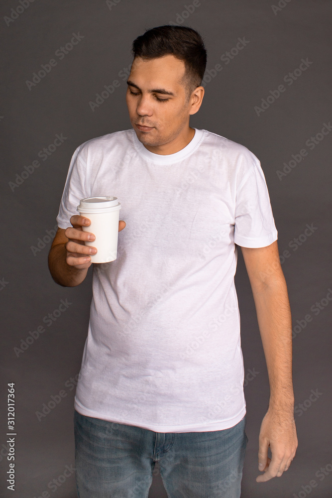 A guy in a white t-shirt is drinking coffee and trying to Wake up and cheer up. A guy in a white t-shirt is drinking coffee and trying to Wake up and cheer up.