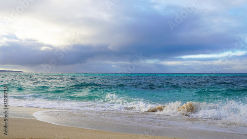 Tropical beach white sand, blue clear ocean water. sea ​​foam on the beach on a sunny day. sea waves on the shore. surf breaking on shore at sunset