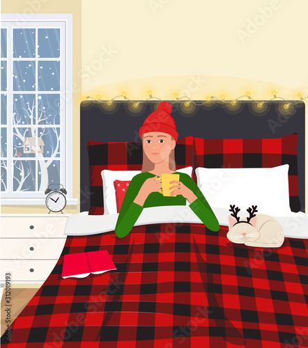 A young girl drinking a hot drink in bed with checkered bed linen.