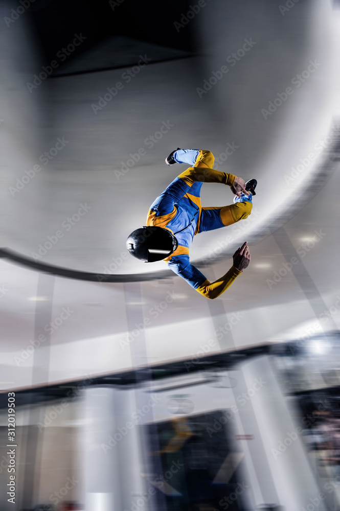 High. Man flies like a bird. Fly men in blue suit. Extreme is a hobby for courage people. Air sport as a way of life.