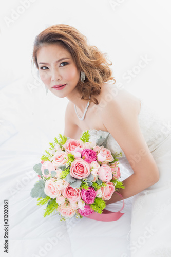 Asian bride sitting with a bouquet of flowers..