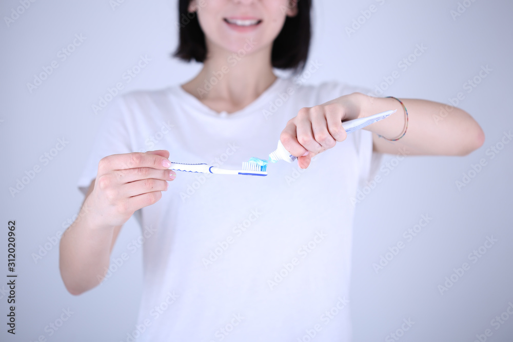 Young woman holding a toothbrush and placing toothpaste on it.