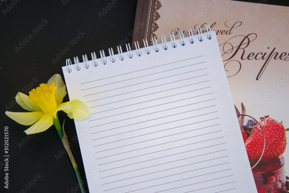 Naklejka premium Fresh spring yellow daffodil flower, empty textbook paper with empty place for text, copy space, romantic concept, black background