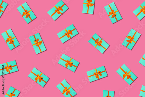 Orange bow on a mint boxes located on pink background.