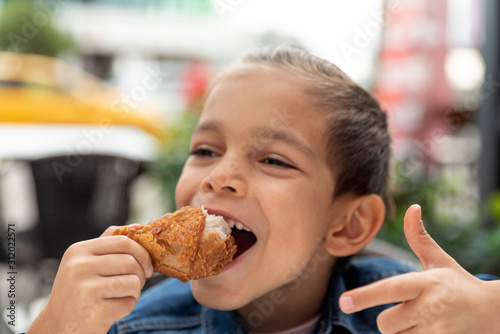 little boy eats fried chicken