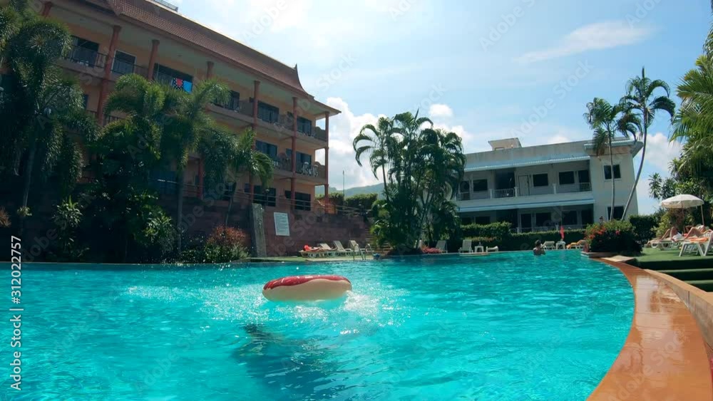 Resort swimming pool and a lady diving with a floating ring Resort swimming pool and a lady diving with a floating ring