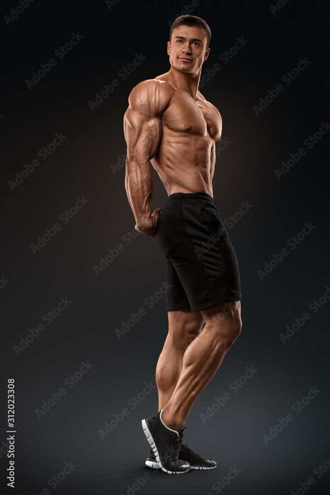 Muscular and fit bodybuilder fitness male model posing over black  background. Strong and handsome young man demonstrate his muscular torso  and biceps. Body of muscular male with great physique Photos | Adobe