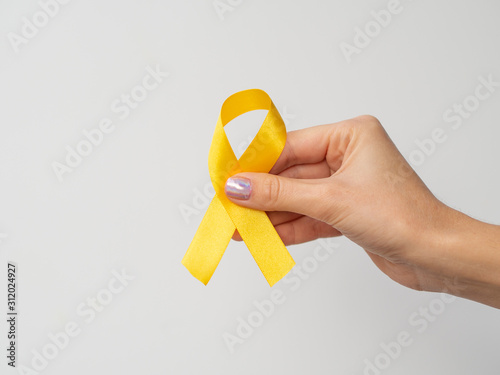 Hand holding gold ribbon on white background. International Childhood Cancer Day. February 15 symbol