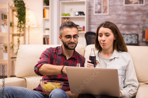 Caucasian couple drinking soda and eating chips
