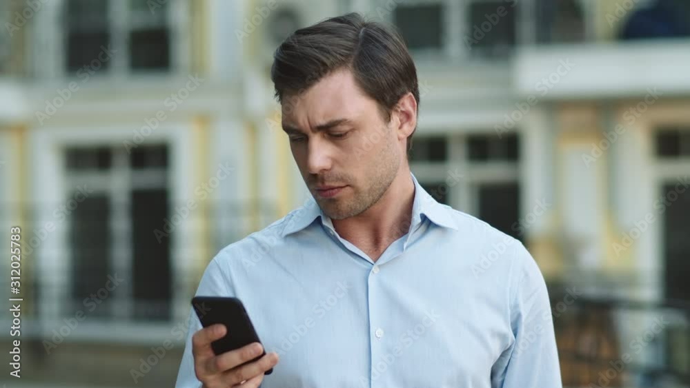 Closeup man typing on phone at street. Businessman using smartphone outdoors