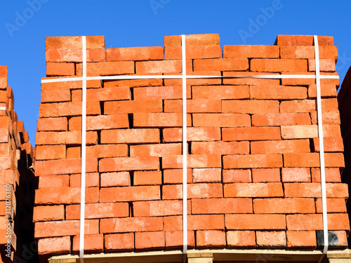 Red bricks stacked into cubes. Warehouse bricks. Storage brickwo