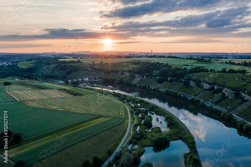 Aerial view of a rural vineyards area nearby a river at sunset, dramatic sky
