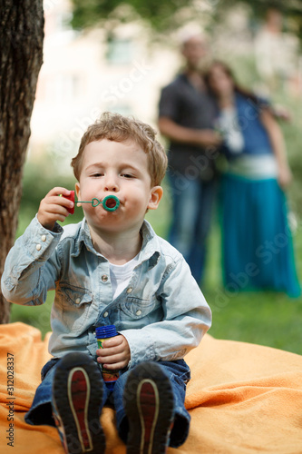 Cute funny toddler boy playing with soap bubbles