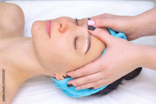 Young woman enjoying massage in spa salon. Face massage. Closeup of young woman getting spa massage treatment at beauty spa salon.Spa skin and body care. Facial beauty treatment.Cosmetology.