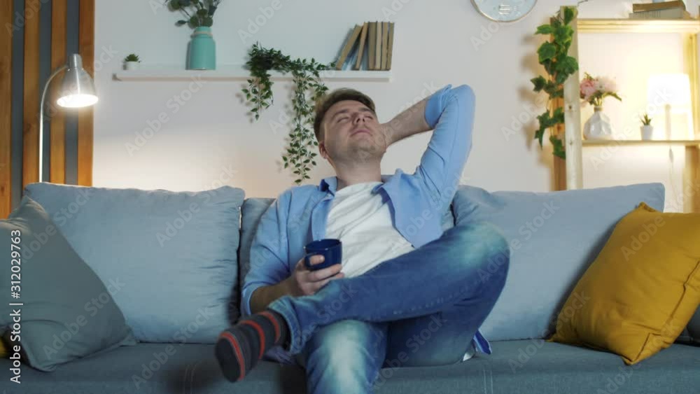 Man in Modern Living Room Relaxing on Couch. Happy Healthy Young Man Resting Holding hand Behind Hand on Sofa. Man in Modern Living Room Relaxing on Couch. Happy Healthy Young Man Resting Holding hand Behind Hand on Sofa.