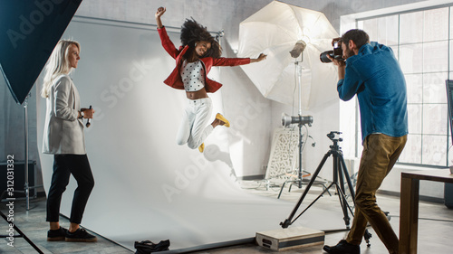 Backstage of the Photo Shoot: Moment Photographer Taking Photos of Jumping Beautiful Black Model with Professional Camera. Fashion Magazine Studio Photoshoot photo
