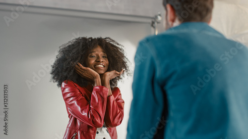 Attractive Black Girl Posing for a Fashion Magazine Photoshoot. Beautiful Girl Smiles during Professional Studio Photo Shoot for Fashion Magazine. She Wears Red Faux Leather jacket
