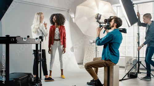 Cameraman Filming Make-up Artist Applies Makeup to a Beautiful Black Model. They Pose for a Video Clip. Stylish Fashion Magazine. Photo Shoot done with Pro Equipment in a Studio photo