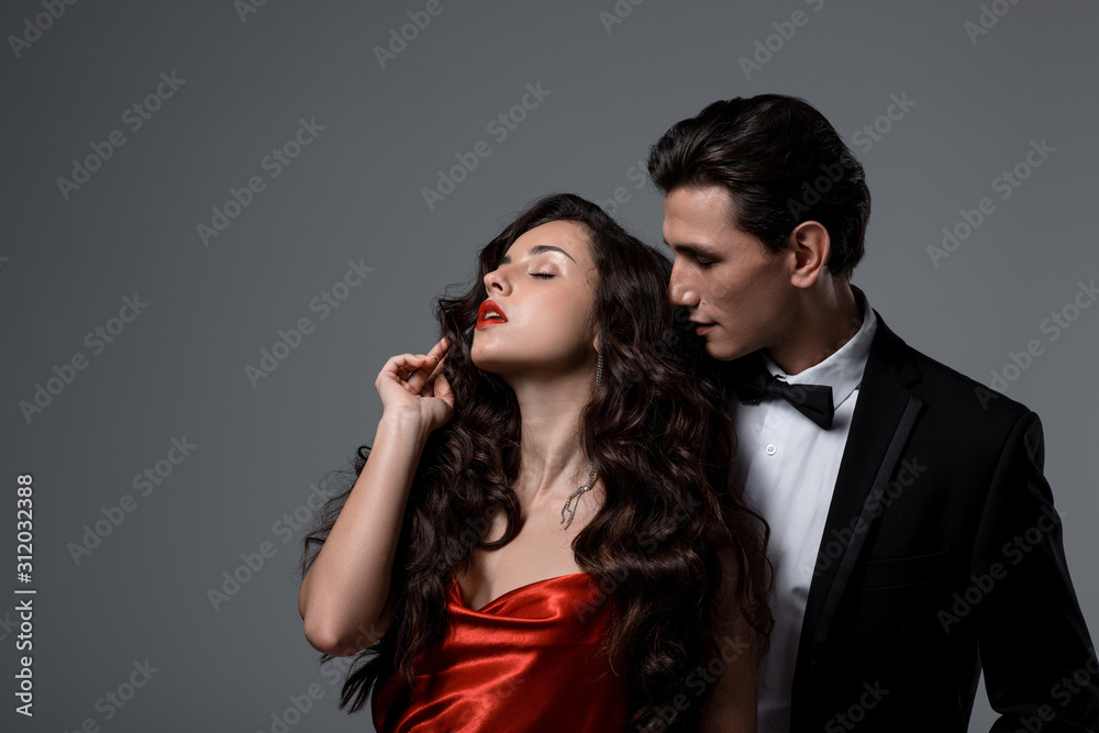 beautiful passionate couple in suit and red silk dress hugging isolated on grey beautiful passionate couple in suit and red silk dress hugging isolated on grey