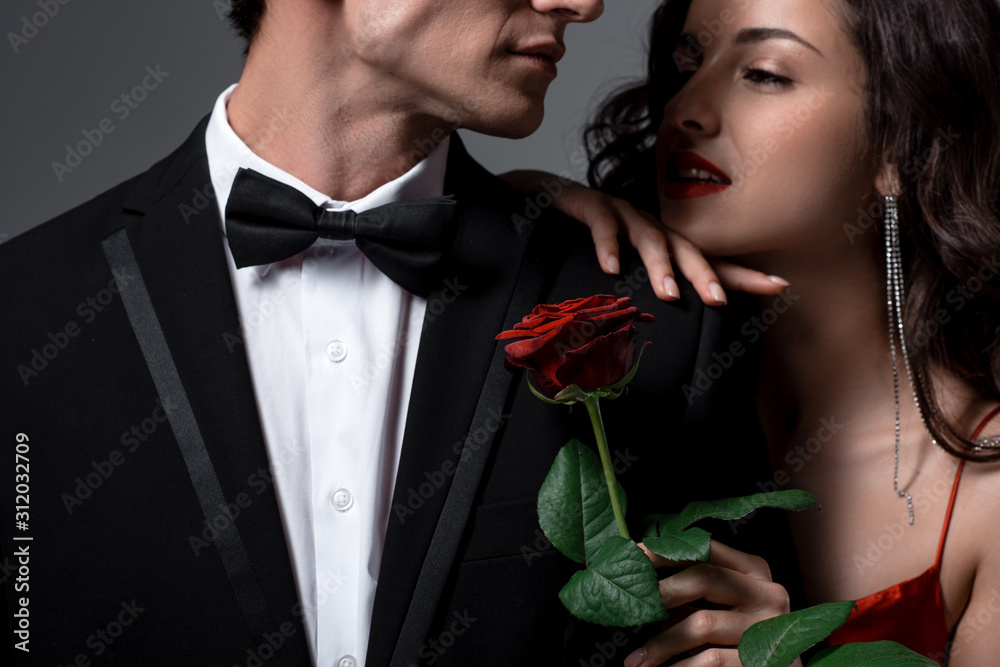 Romantic couple hugging and holding red rose flower isolated on grey Romantic couple hugging and holding red rose flower isolated on grey