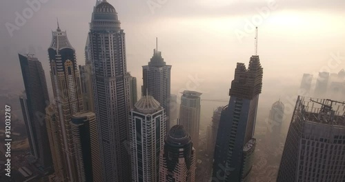 DUBAI, UAE - JANUARY 2, 2017: Aerial view of skyscrapers in Dubai Marina, at foggy sunrise. Dubai Marina is an artificial canal city, built along a two-mile (3 km) stretch of Persian Gulf shoreline.