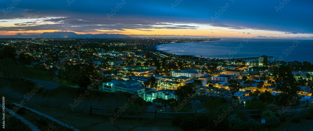 Twinkling lights of the Ventura cityscape shine as dawn begins to break over hilltop horizon and cast light onto the Pacific Ocean.