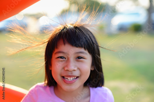 The little girl is smiling happily. Maybe because her hair is slightly fluffing up from static electricity.
