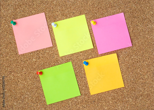 Cork board with several colorful blank notes with pins