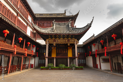 Beautiful, traditional building with red lanterns in Yu Garden, Shanghai, China, under a moody, cloudy sky