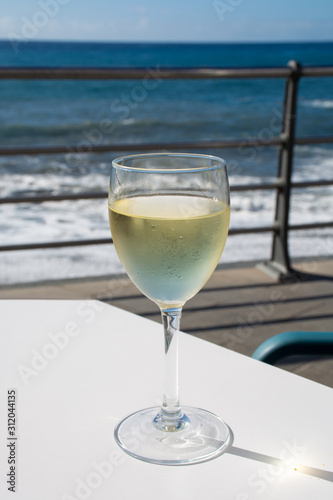 Summer holiday on sea, drinking white wine on outdoor terrace with sea view in sunny day