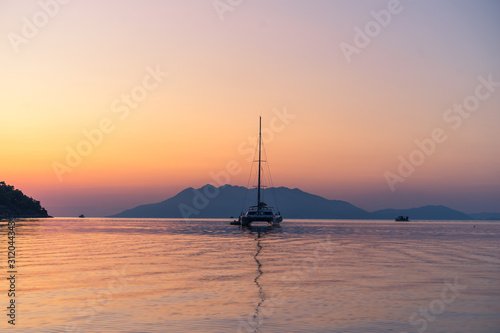 Scenic beautiful sunrise with a view on a boat at the marine of Epidaurus Island, Peloponnese, Saronic Gulf, Greece. 