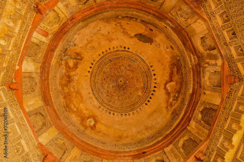 A design inside of bara gumbad monument at lodi garden or lodhi gardens in a city park from the side of the lawn at winter foggy morning.