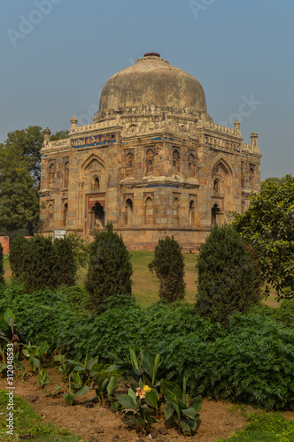 A shish gumbad monument at lodi garden or lodhi gardens in a city park from the side of the lawn at winter foggy morning.