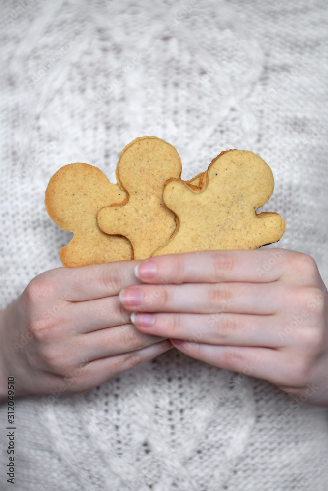 Obraz premium Gingerbread men in woman hand against the white knitted sweater