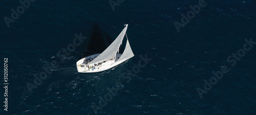 Aerial drone ultra wide photo of beautiful sailboat cruising in Aegean deep blue sea