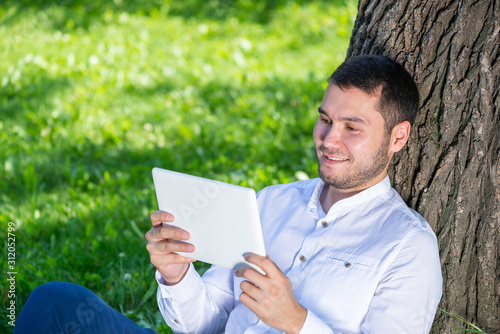 Man using tablet computer under tree in park