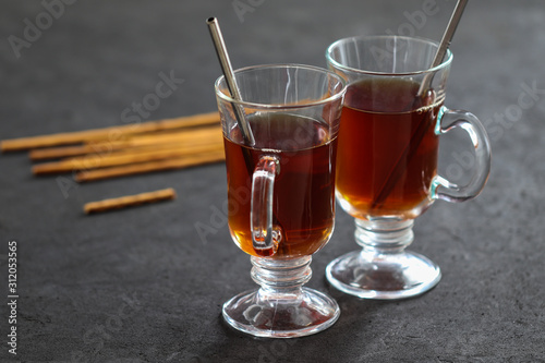 Black tea in a glass with cookies straws on a dark gray background
