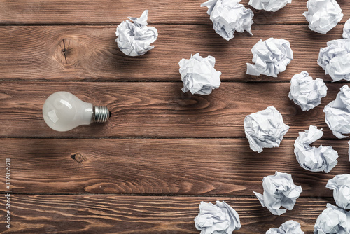 Ideological concept with wastepaper light bulb on wooden table