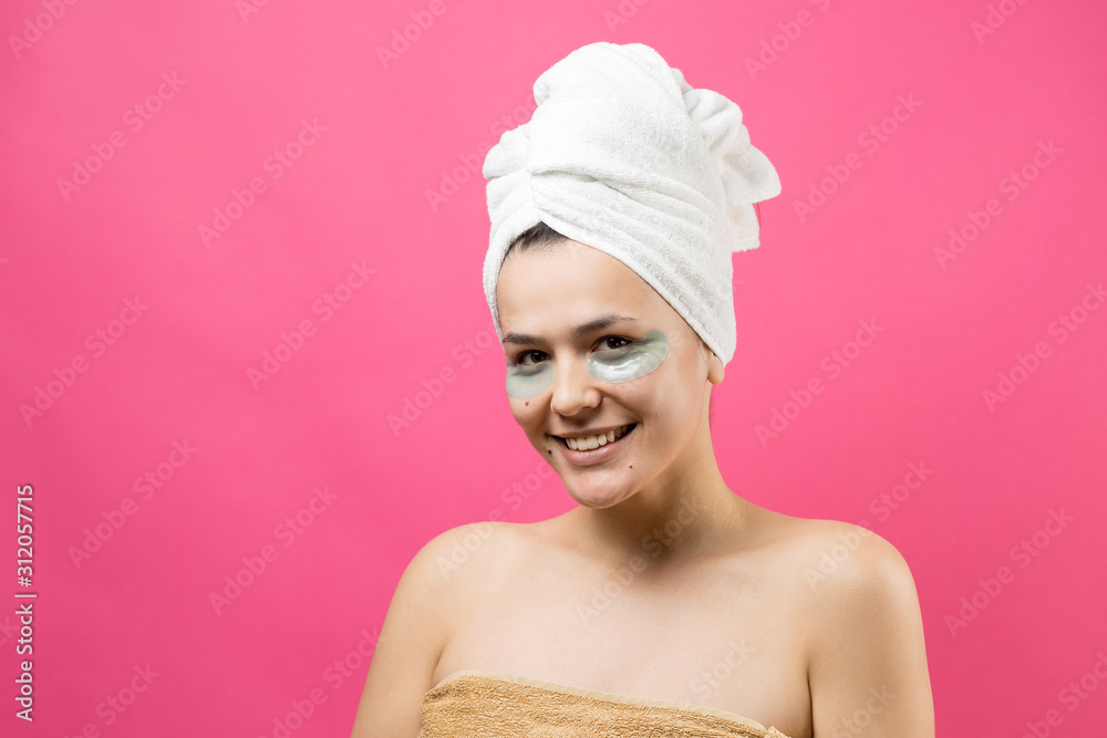 Young beautiful girl in a white towel on his head wears collagen gel patches under her eyes. Mask under eyes treatment face. Young beautiful girl in a white towel on his head wears collagen gel patches under her eyes. Mask under eyes treatment face.