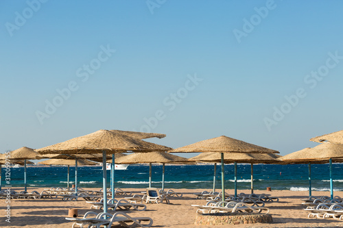 Beach umbrellas on the coastline of the sea at sunset.